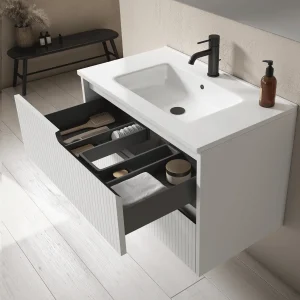 Mueble de baño Ezio con lavabo de porcelana y tres cajones con patas en negro, con cajón abierto en blanco