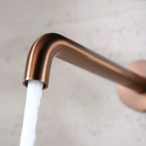 Grifo de lavabo empotrado monomando serie Bless de Imex, con agua saliendo del caño en oro rosa